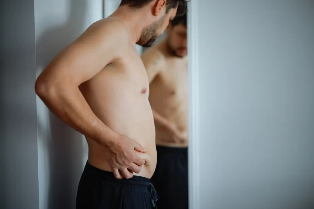 Man looking at belly in mirror